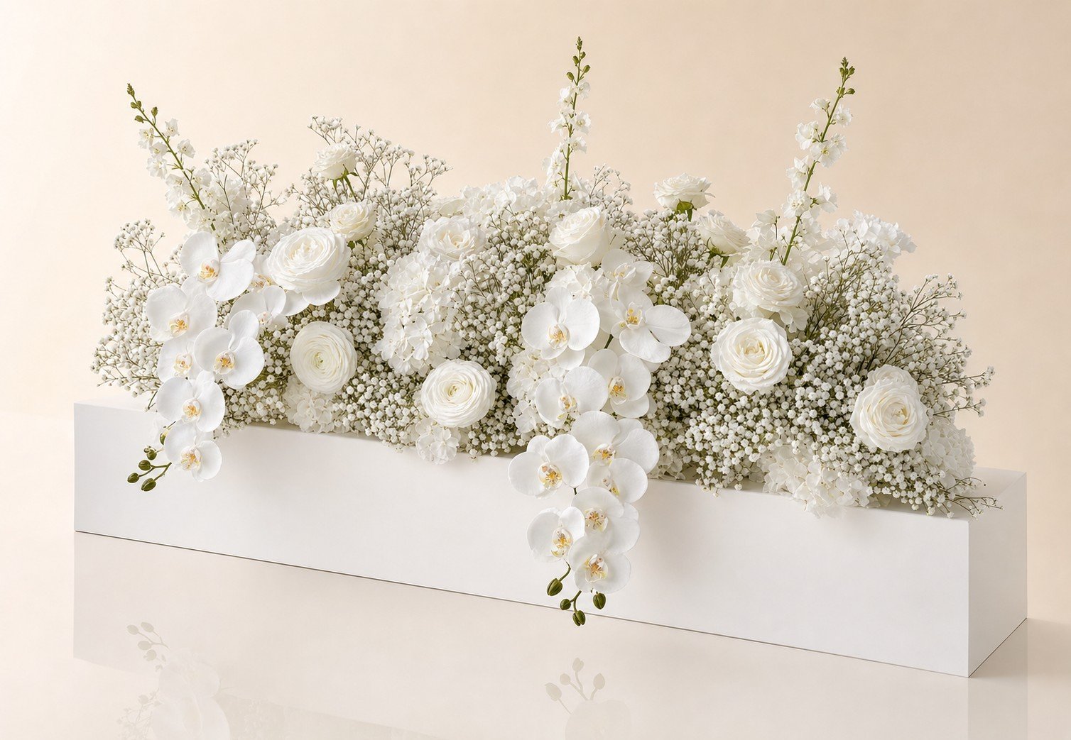 Long low centerpiece with white orchids, roses and babys breath