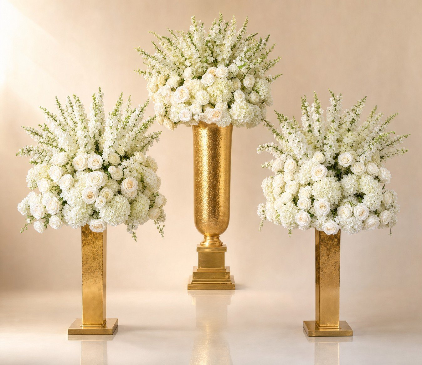 Trio of tall white floral pedestals with gold urn centerpiece